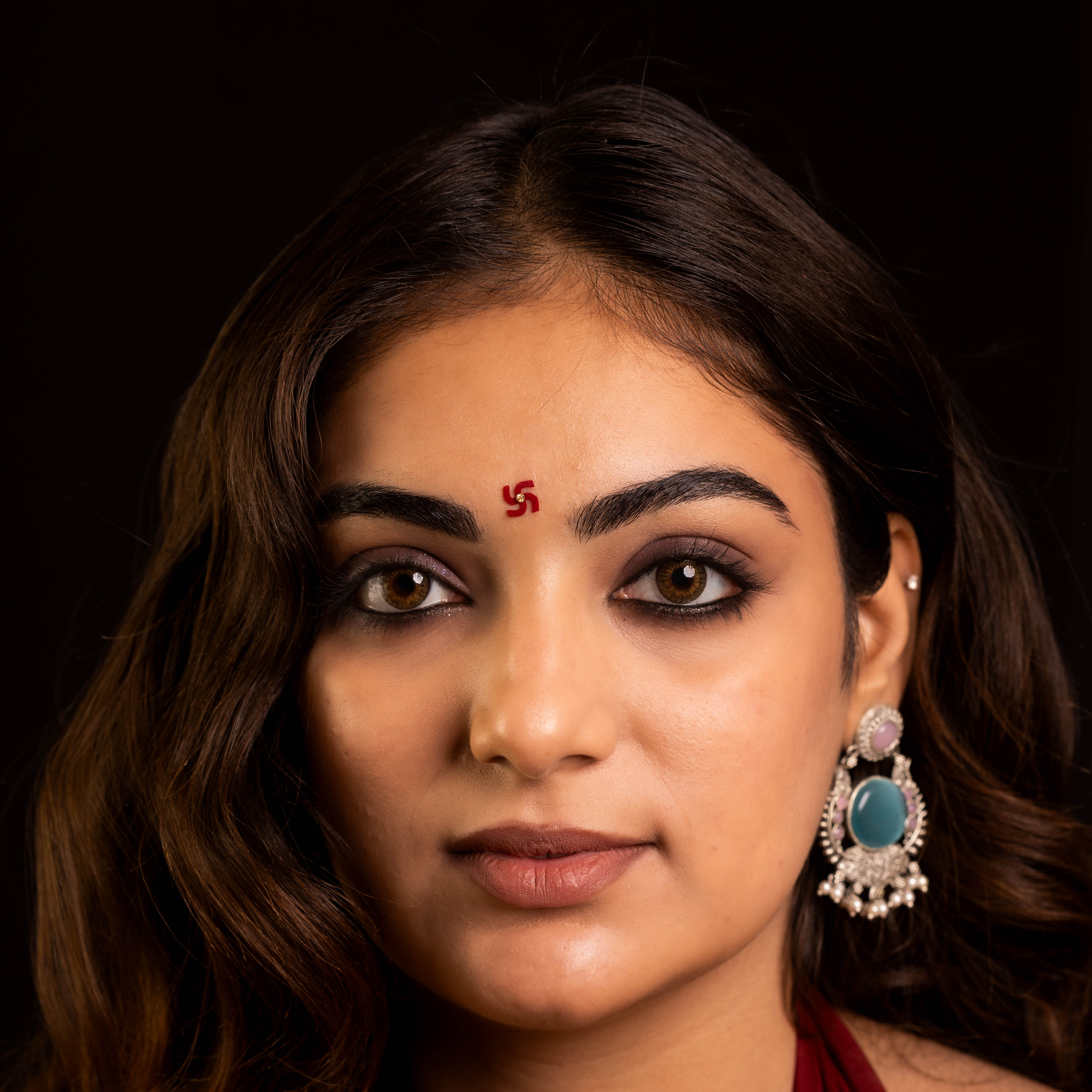 Comet Busters Maroon Swastik-shaped designer bindi featuring a gold crystal stone at the center, inspired by the auspicious Hindu symbol for prosperity, positivity, and spiritual significance.